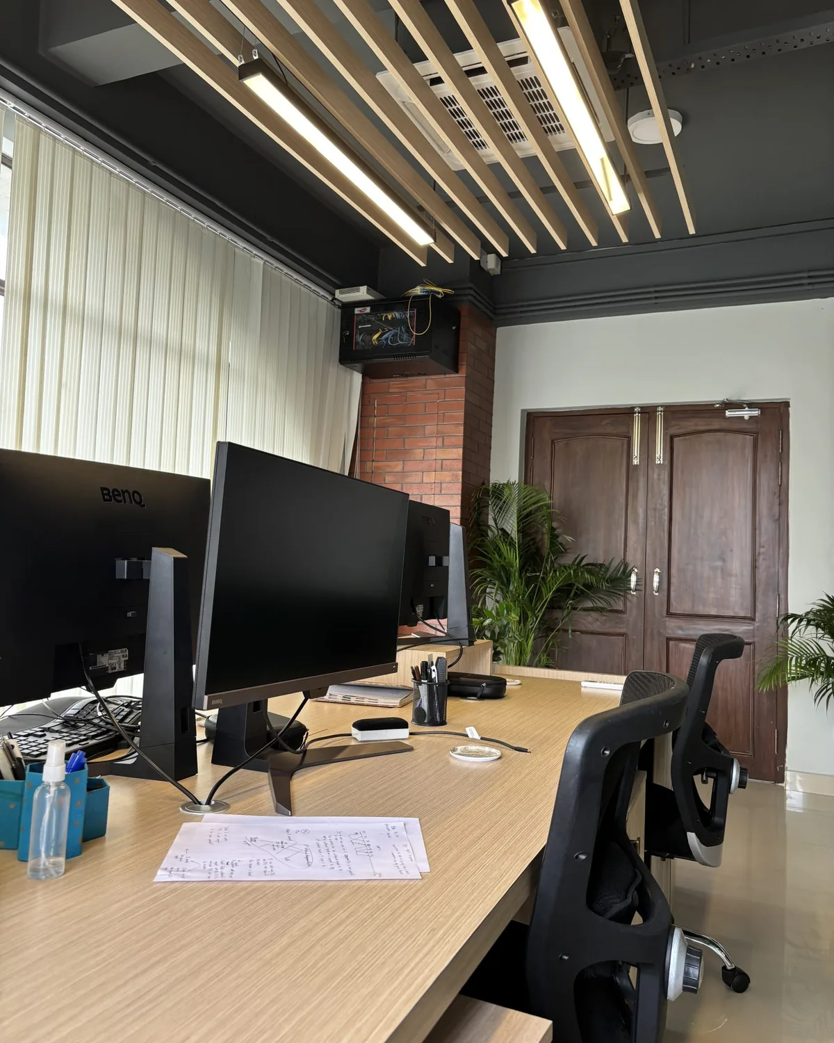 Office workstation with two monitors and paperwork on the desk